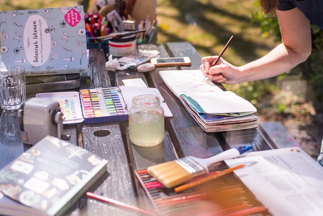 photo table atelier peinture avec ustensiles et personnes qui peint sur un carnet de croquis